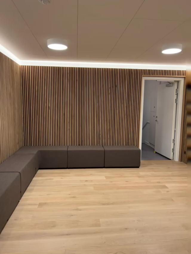 Loungesofa i venteområde med smuk akustikvæg i baggrunden i egetræ til at dæmpe lyden