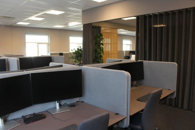 Indret kontoret med gardiner, grønne planter og en varm farvepalette for at skabe en god atmosfære på arbejdspladsen