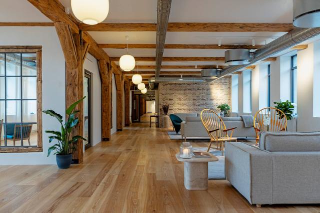 Venteområde indrettet med flotte designmøbler, Louis Poulsen pendler og tæpper i varme rolige farver