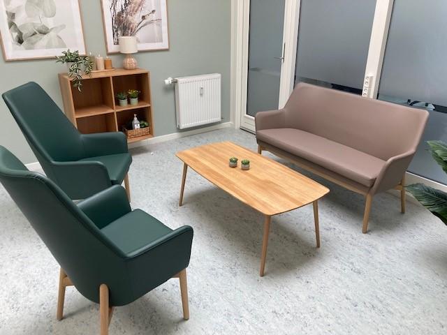 Flot og varm venteområde møbleret med sofaer, lænestole og sofabord i egetræ